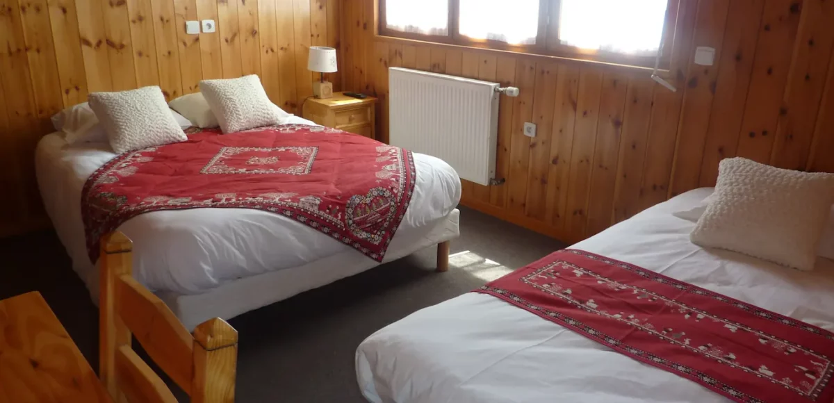 Chambre en bois avec deux lits et jetés brodés rouges