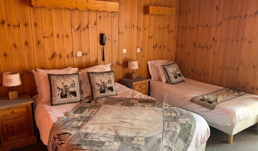 Chambre en bois avec deux lits et dessus-de-lit motifs vintage