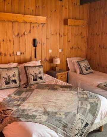 Chambre en bois avec deux lits et dessus-de-lit motifs vintage
