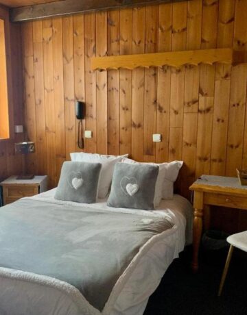 Chambre avec lit gris, coussins cœur et bureau