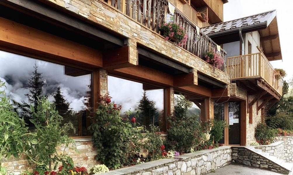 Façade en pierre et bois de l'hôtel avec fleurs en été
