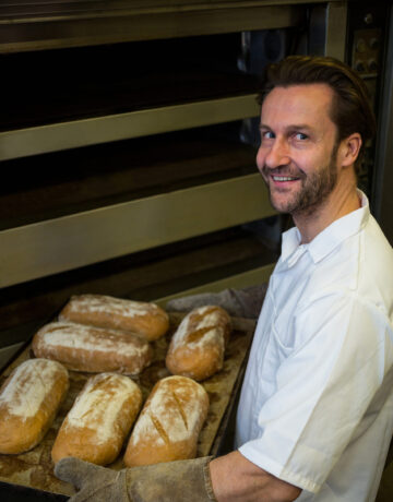 Boulanger souriant sortant des pains maison du four