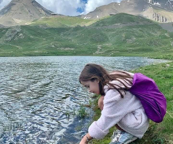 Enfant accroupie au bord d'un lac de montagne à Orcières Merlette