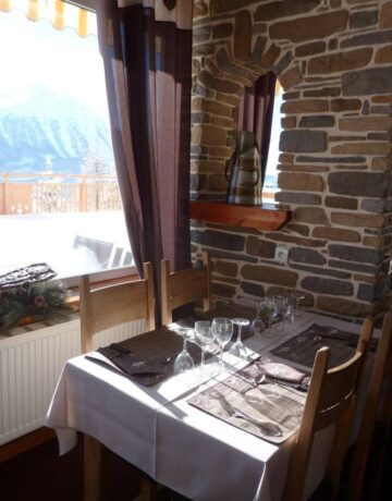 Table dressée en salle de restaurant avec vue sur les montagnes