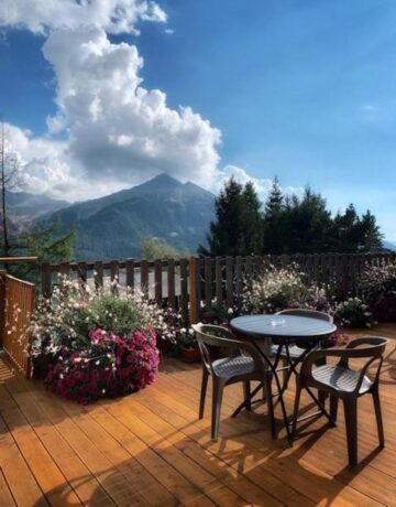 Terrasse extérieure avec table, fleurs et vue sur les montagnes