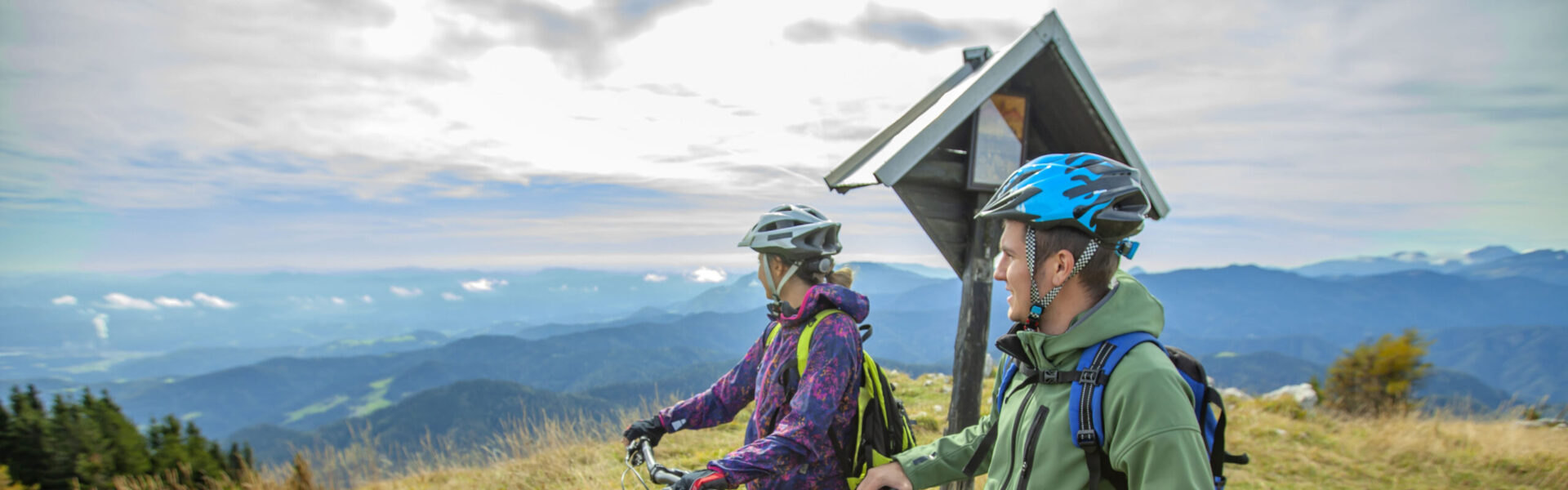 Deux vététistes en pause au sommet avec vue panoramique sur les montagnes