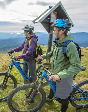 Deux vététistes en pause au sommet avec vue panoramique sur les montagnes