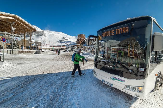 Navette gratuite de la station en hiver, skieur portant ses skis à l'arrêt à Orcières Merlette